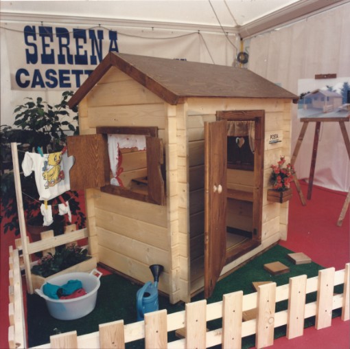 casetta di legno per il gioco dei bambini racchiusa in una minuta staccionata in legno, tendine alla finestra e panni stesi su piccolo stenditoio